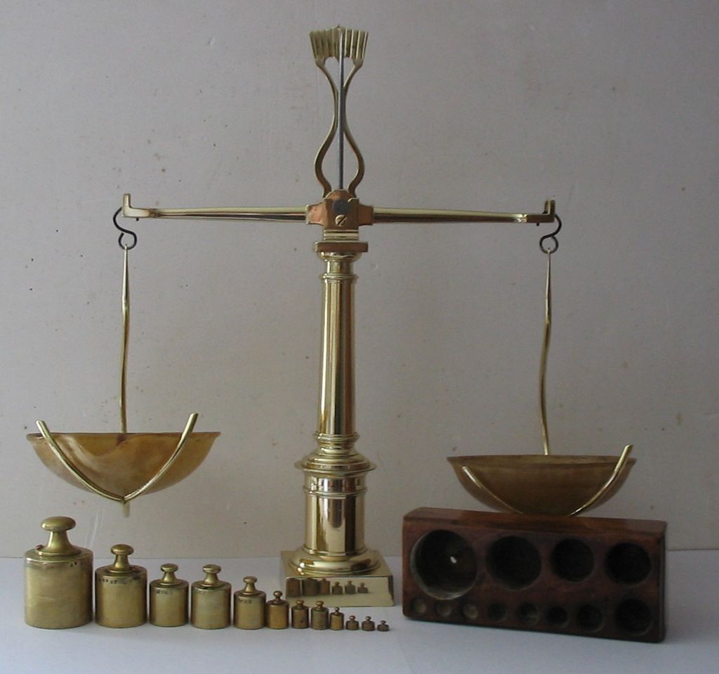 A brass scale with two bowls and a bottle.