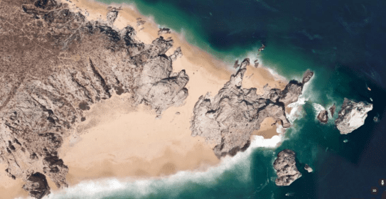A satellite image of a beach with sand and rocks.