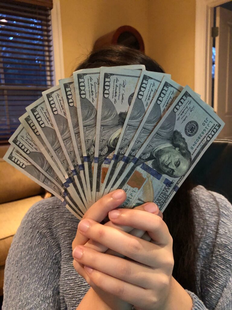 A Woman Holding Out a Bunch of Dollar Bills