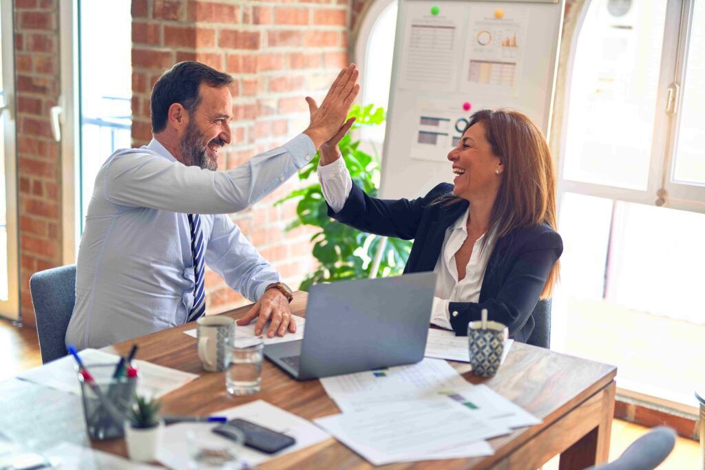 A businessman and woman giving each other a high five in an office.