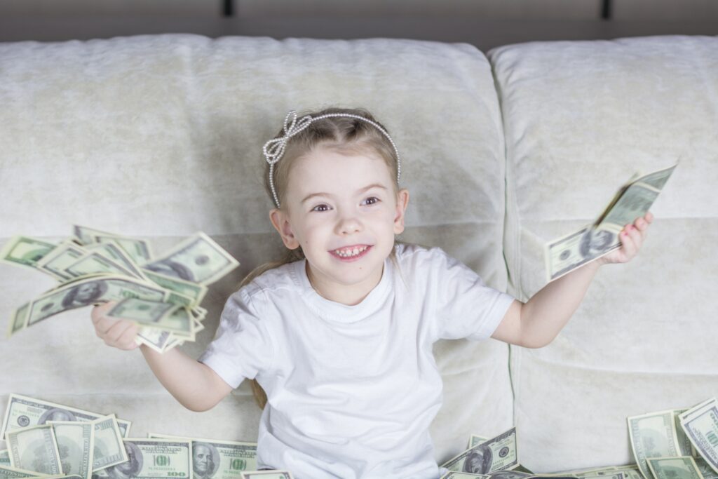 A little girl sitting on a couch with money in her hands.