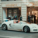Luxury cars parked outside Versace store.